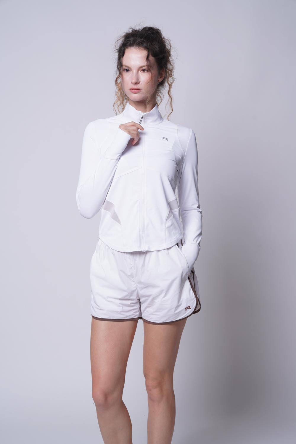 female model wearing the ramsports Flow Panel Split-Hem Short in white with white long sleeves