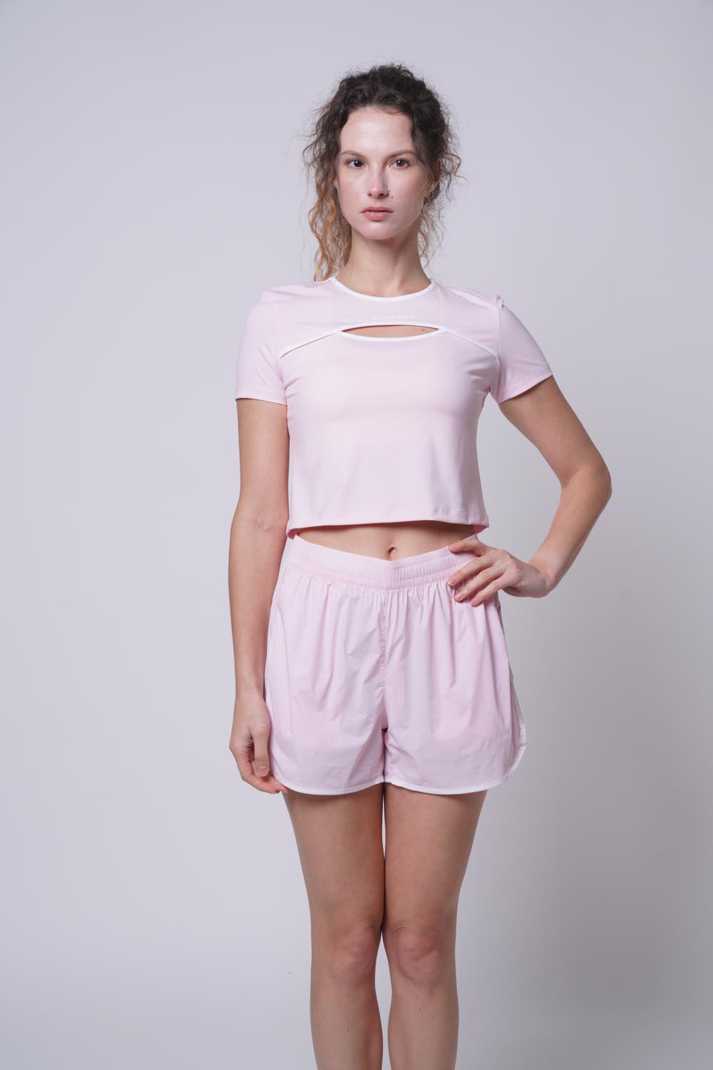 Female model with her hand on her right hip wearing ramsport arcBand crew tee
in pink