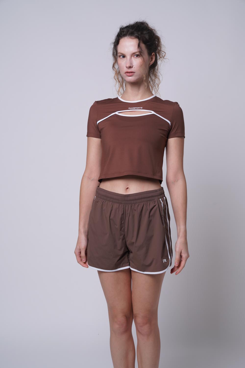 Female model looking away, wearing ramsport arcBand crew tee in brown