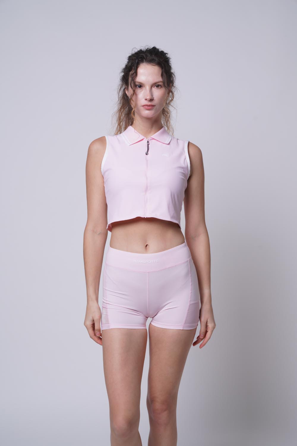 Female model standing straight, wearing Ramsports serve zip crop polo in pink