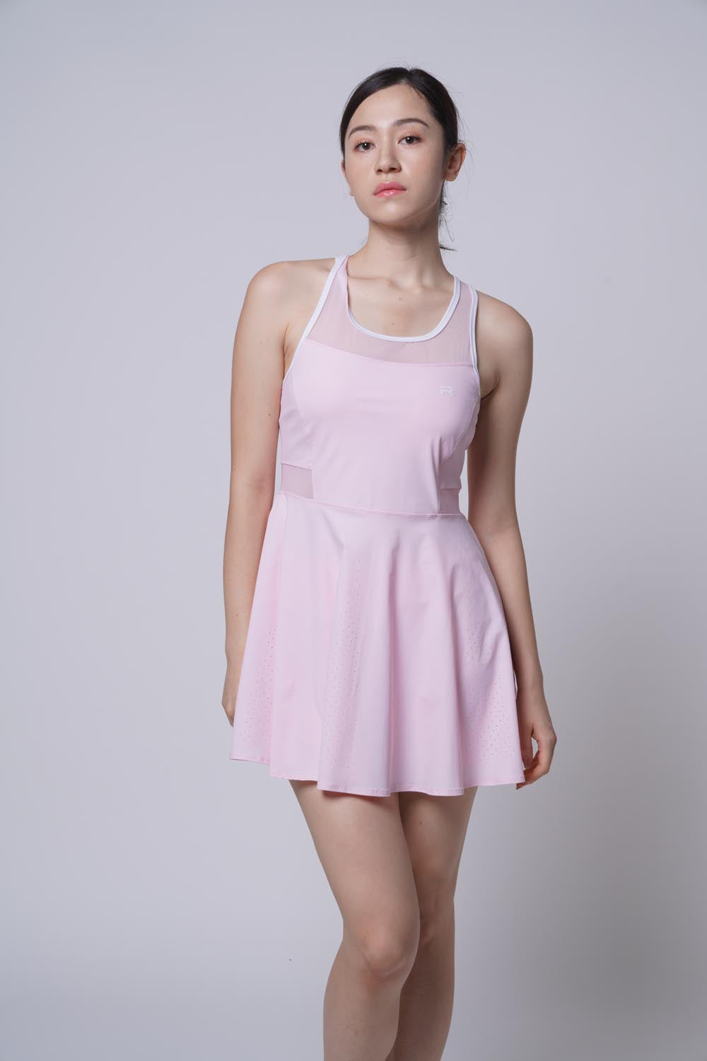 Asian female model standing with one leg bent in front as she's wearing the Ramsports Racer Flare Dress in pink