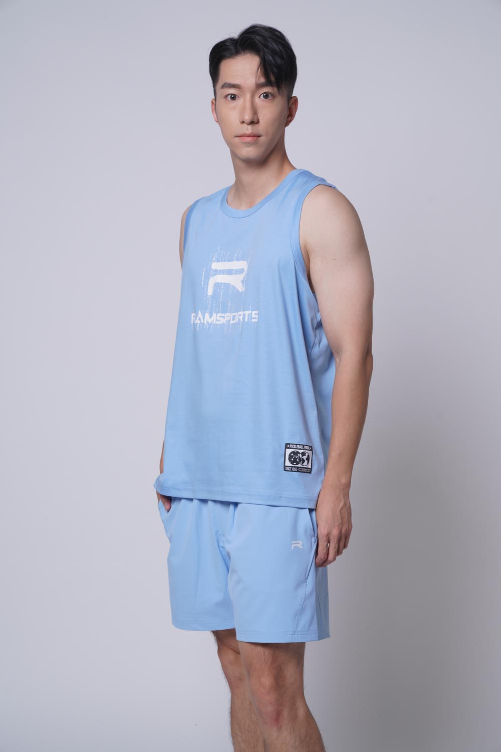 Asian male model looking at the camera, as he's wearing Ramsports repMark tank in blue