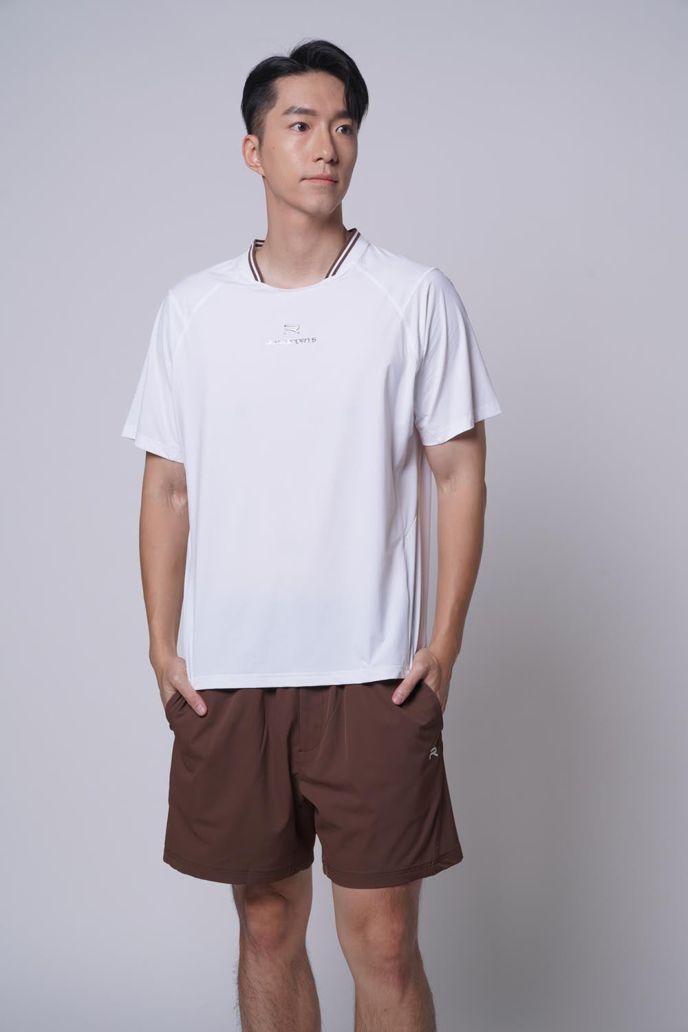 Male mode looking away from the camera with both hands on pocket, wearing ramsports Edge Line Raglan Tee in white