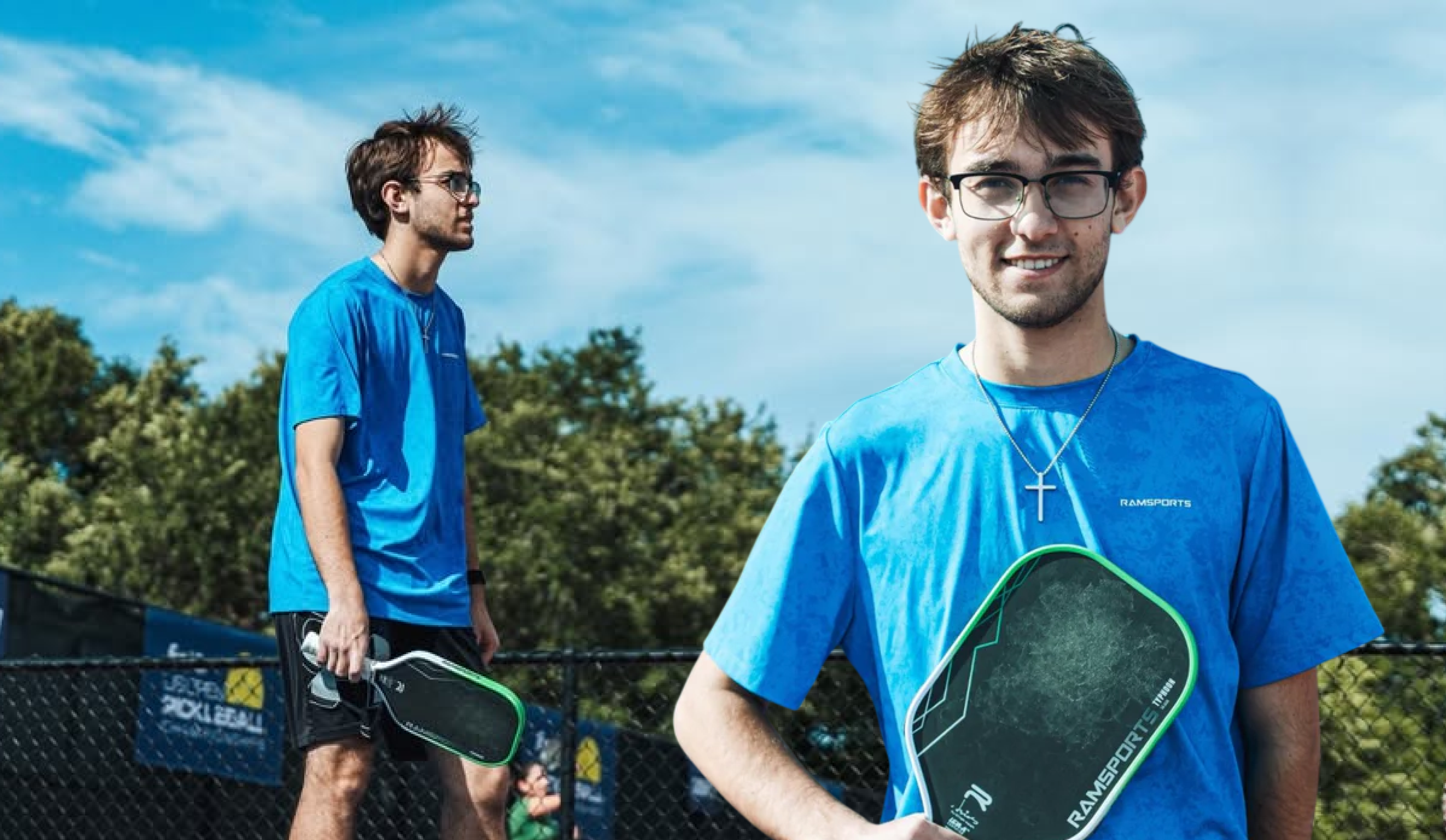Pickleball player Connor Duvall in a blue Ramsports tee, holding a green Ramsports paddle courtside