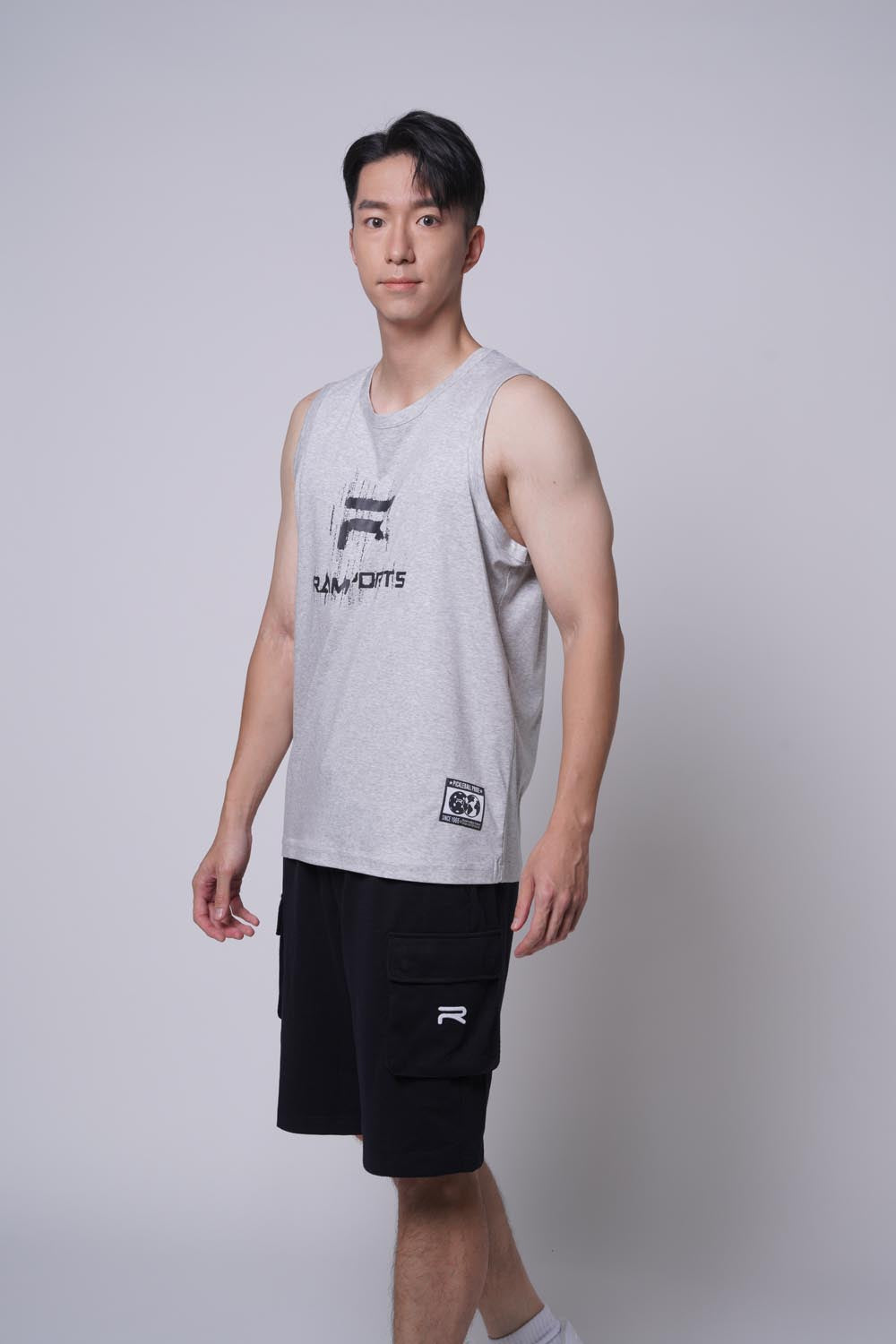 Asian male model standing sideways as if he's walking, wearing Ramsports Court Cargo Utility Short in black